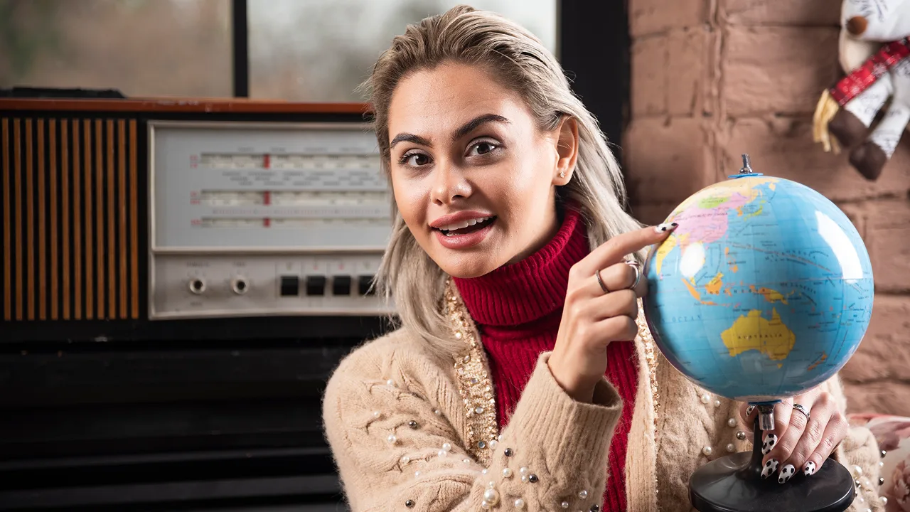 A woman pointing at a globe, representing global learning and education at an expert German language institute in Kochi