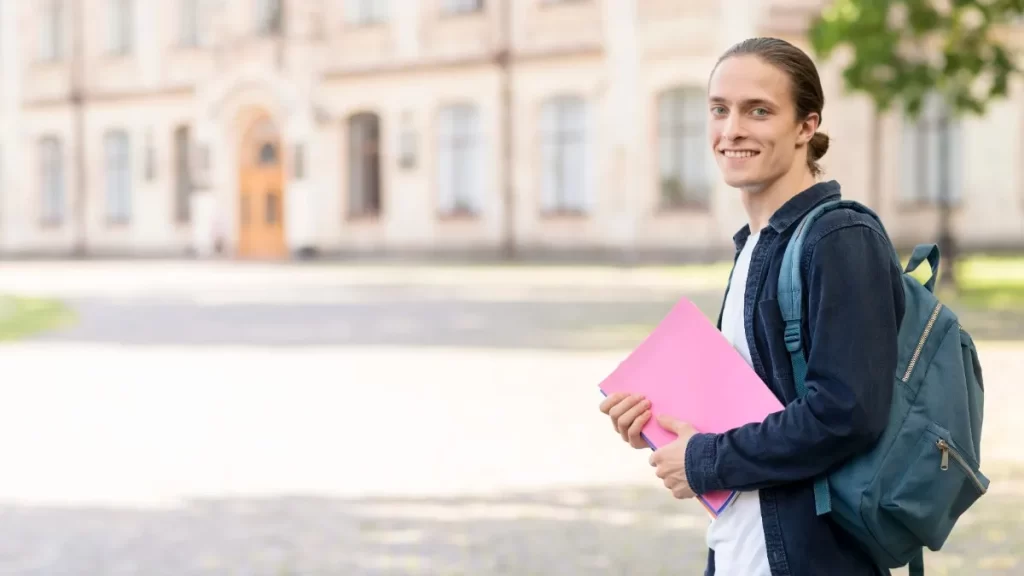 Smiling student carrying books and a backpack outside a university campus — Top German language institute in Kochi